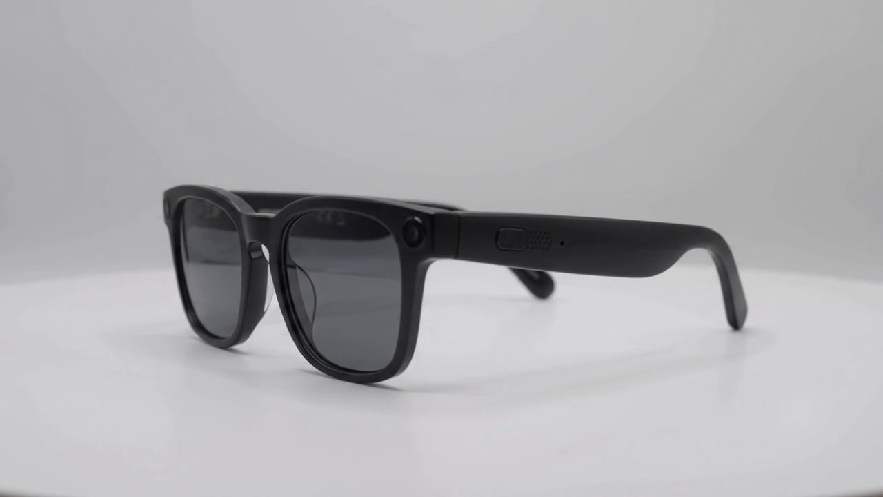 The Blynq glasses, turned to show the recessed button on the outer temple.